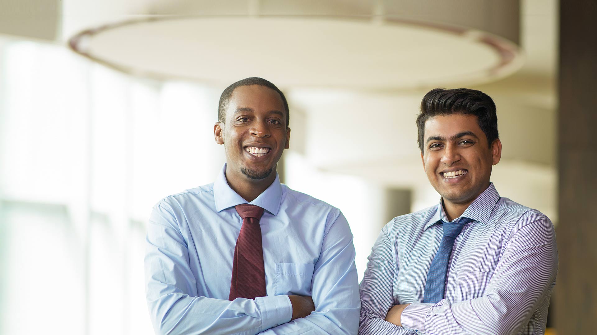 Business people smiling at camera with arms folded.