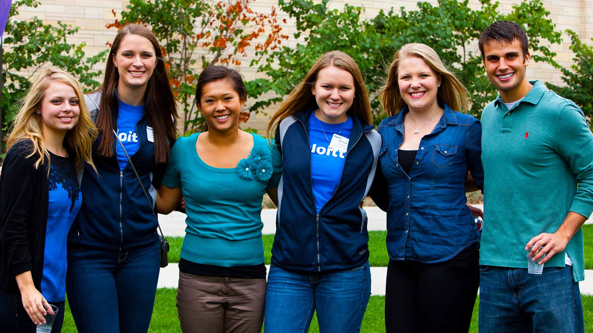 A group of students pose for a picture at a outdoor social event.